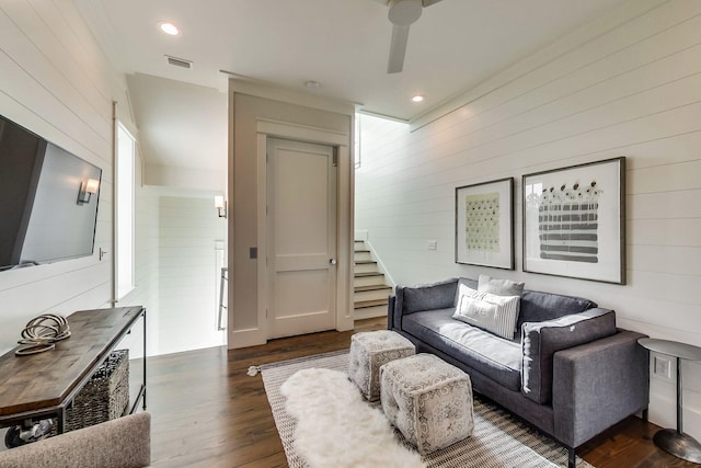 living room featuring ceiling fan, dark hardwood / wood-style flooring, and wood walls