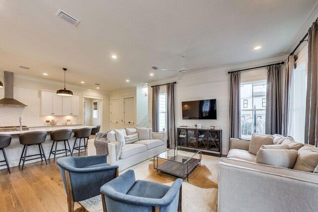 living room featuring light hardwood / wood-style floors, plenty of natural light, ceiling fan, and ornamental molding