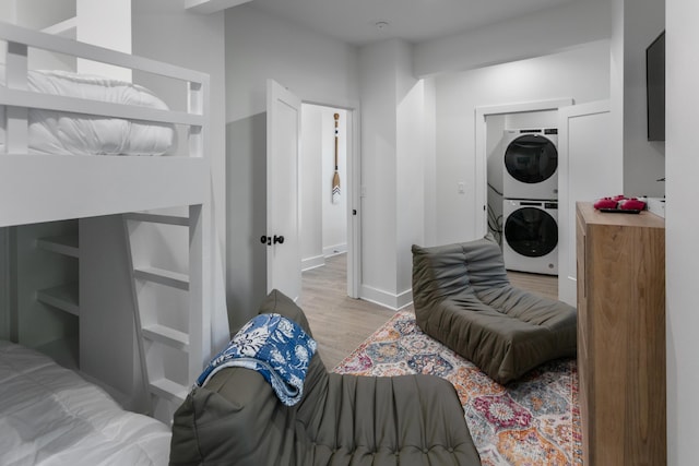 bedroom featuring stacked washer and clothes dryer and light wood-type flooring