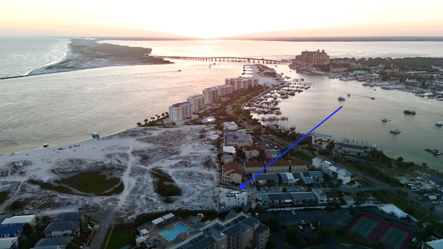 aerial view at dusk with a water view and a beach view