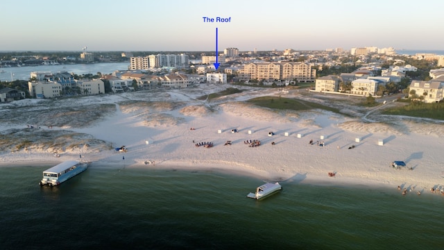 aerial view at dusk featuring a water view and a beach view