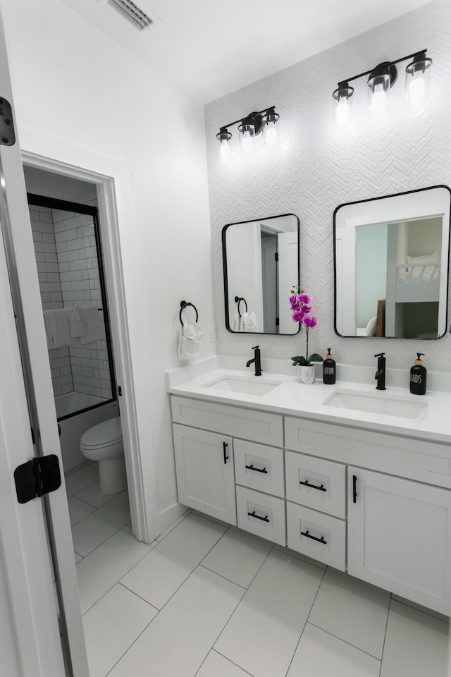 bathroom with vanity, tile patterned floors, toilet, and tiled shower