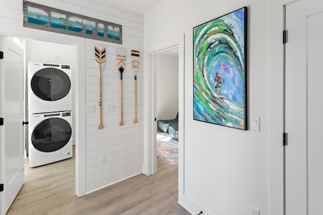 laundry area featuring stacked washer / drying machine and light hardwood / wood-style flooring