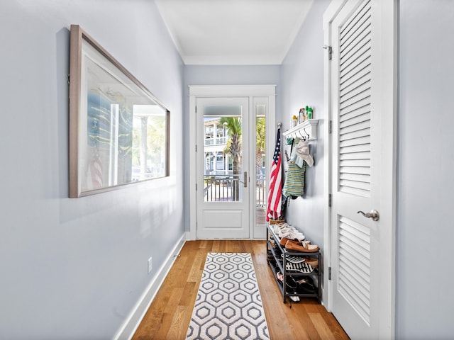 doorway to outside with light hardwood / wood-style floors and crown molding