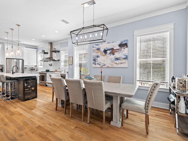 dining space featuring sink, light wood-type flooring, and wine cooler