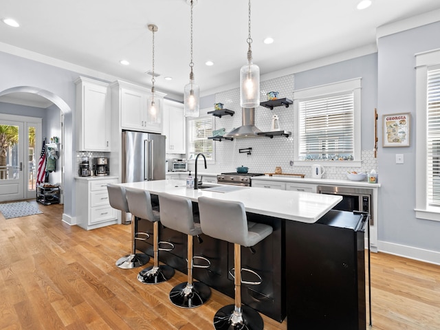 kitchen with a center island with sink, a breakfast bar, white cabinetry, light hardwood / wood-style floors, and decorative backsplash