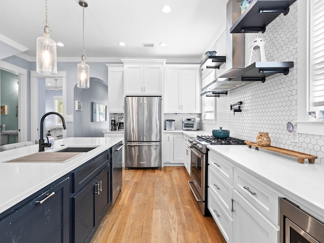 kitchen with sink, stainless steel appliances, white cabinetry, and hanging light fixtures