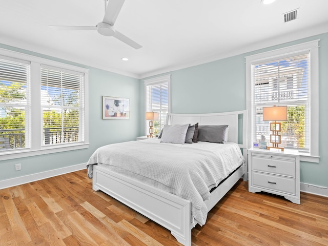 bedroom with multiple windows, ceiling fan, and light wood-type flooring