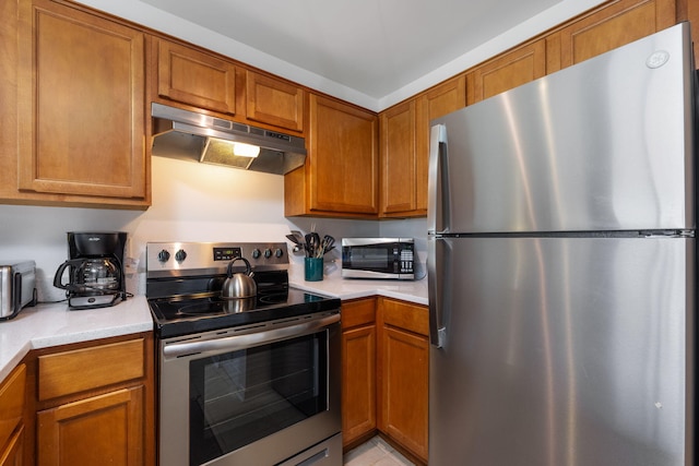 kitchen featuring brown cabinets, under cabinet range hood, stainless steel appliances, and light countertops