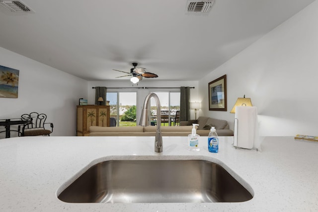 room details featuring light stone counters, a sink, visible vents, and a ceiling fan