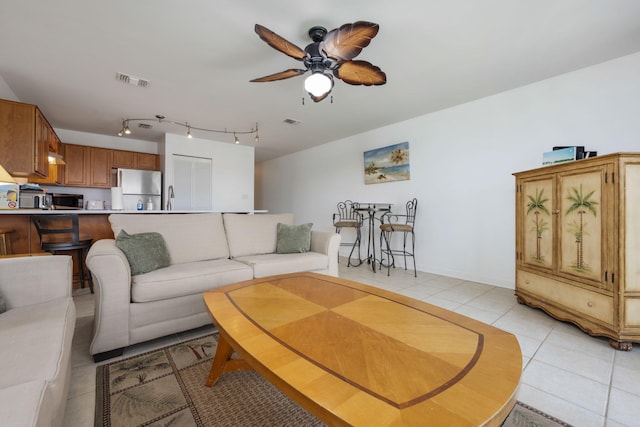 living area with rail lighting, light tile patterned flooring, ceiling fan, and visible vents