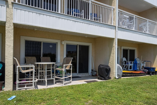 back of house with a patio, a lawn, a balcony, and stucco siding