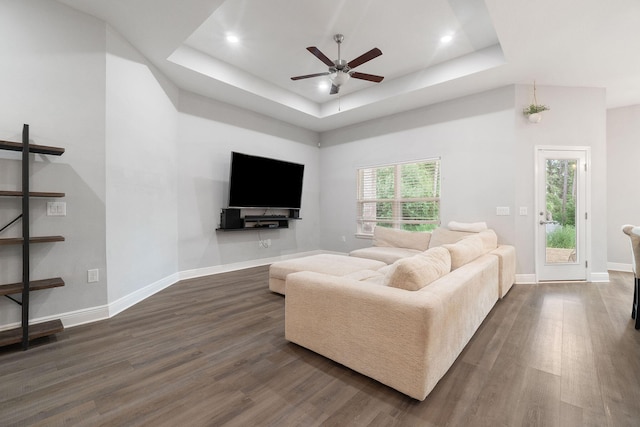 living room featuring dark wood-style floors, baseboards, and a raised ceiling