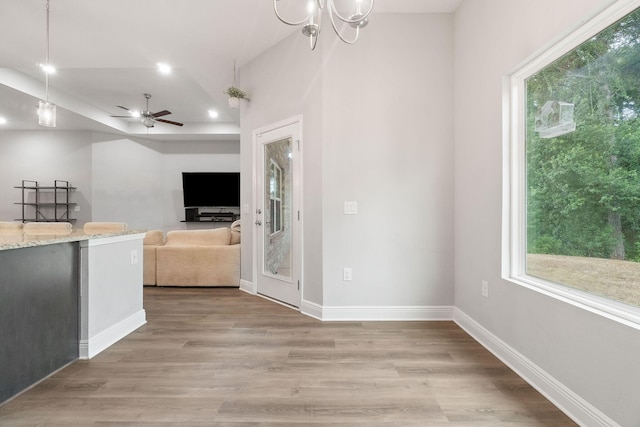 unfurnished living room featuring light wood-style flooring, baseboards, and ceiling fan with notable chandelier