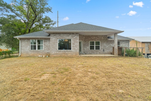 back of house with a patio area, a lawn, and brick siding