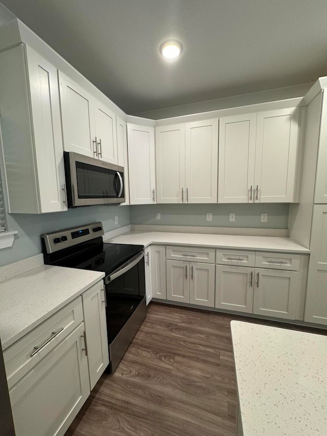 kitchen featuring white cabinets, appliances with stainless steel finishes, and dark wood-type flooring