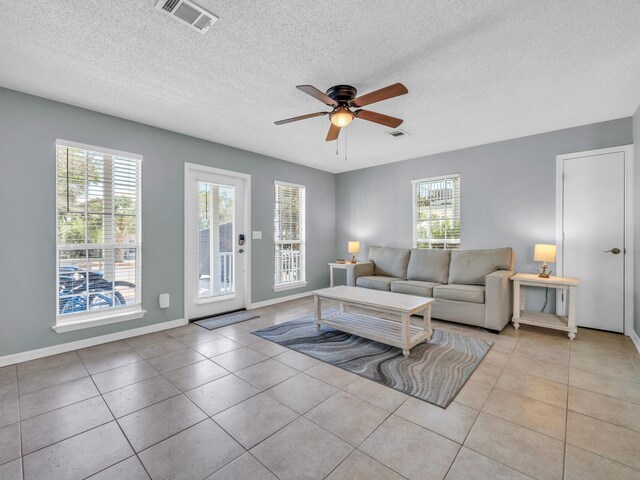 living room featuring light tile patterned flooring, ceiling fan, and a textured ceiling