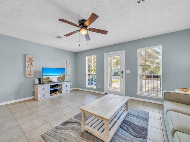 living room featuring a textured ceiling, ceiling fan, and light tile patterned floors