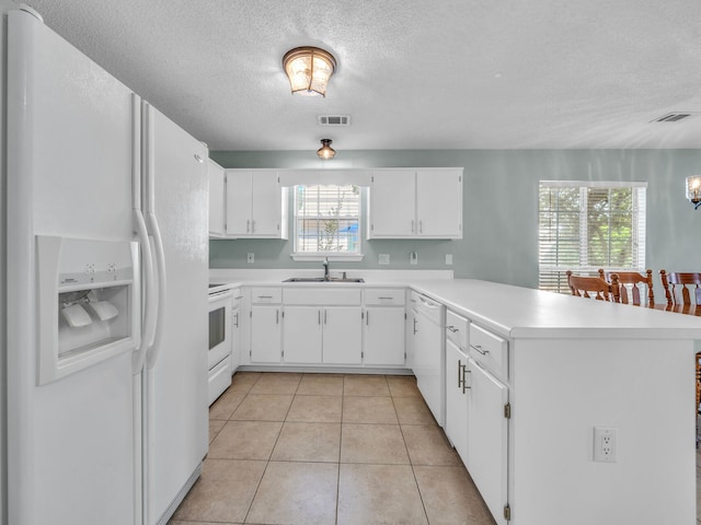 kitchen with light countertops, white cabinetry, a sink, white appliances, and a peninsula