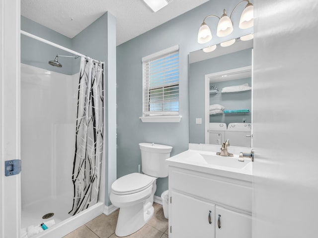 bathroom featuring tile patterned flooring, toilet, vanity, a shower stall, and washer and clothes dryer