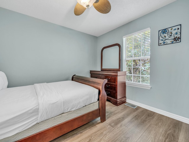 bedroom featuring a ceiling fan, visible vents, light wood-style flooring, and baseboards