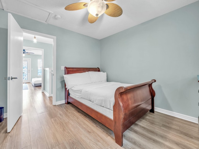 bedroom with light wood-style flooring, attic access, baseboards, and a ceiling fan