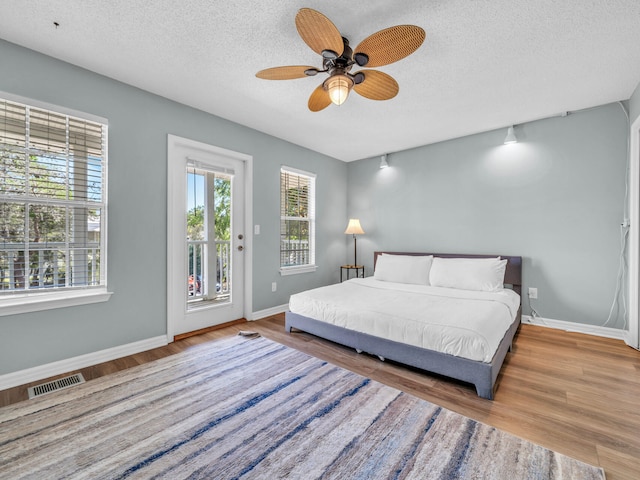 bedroom with access to outside, wood finished floors, and visible vents