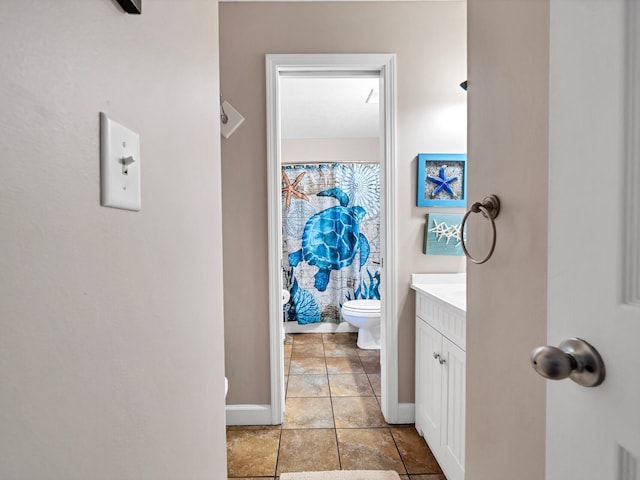 bathroom with toilet, baseboards, and vanity