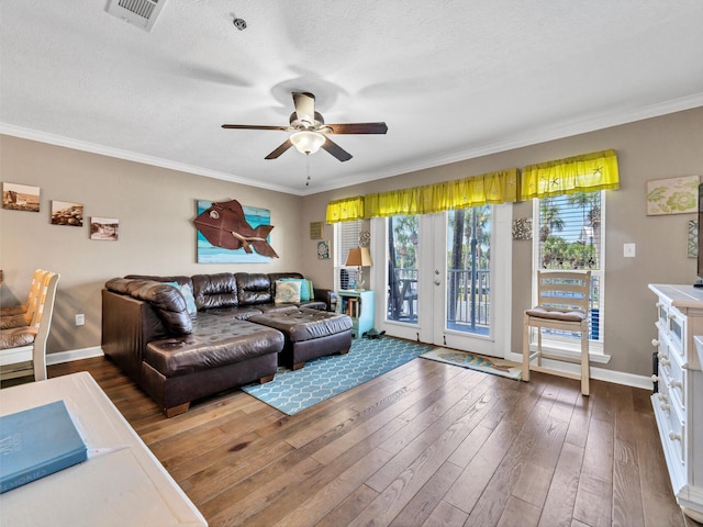 living room featuring baseboards, visible vents, dark wood-type flooring, and ornamental molding