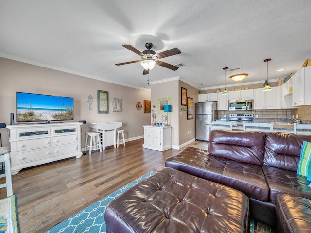 living area featuring crown molding, dark wood finished floors, visible vents, ceiling fan, and baseboards