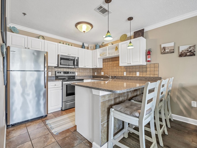 kitchen with appliances with stainless steel finishes, decorative backsplash, crown molding, kitchen peninsula, and a breakfast bar