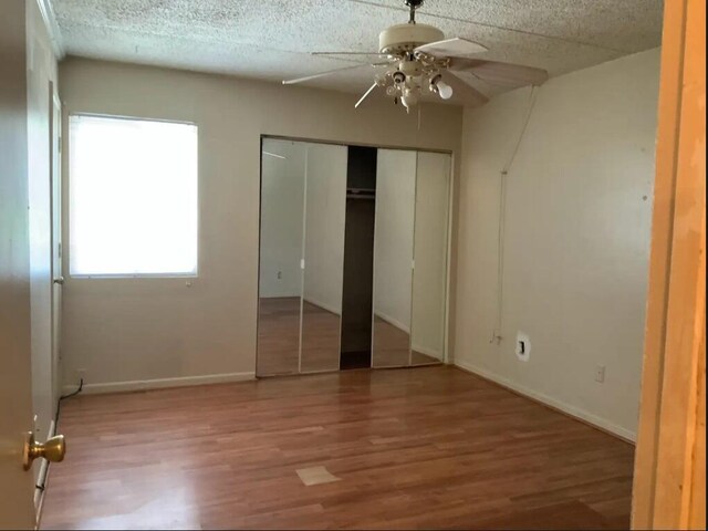 unfurnished bedroom with ceiling fan, wood-type flooring, and a textured ceiling