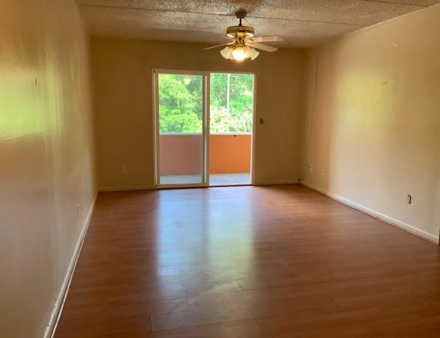 empty room with ceiling fan, hardwood / wood-style flooring, and a textured ceiling