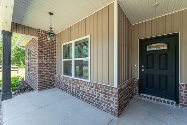 property entrance with a porch and brick siding