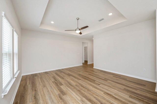 unfurnished room featuring ceiling fan, a raised ceiling, and wood-type flooring