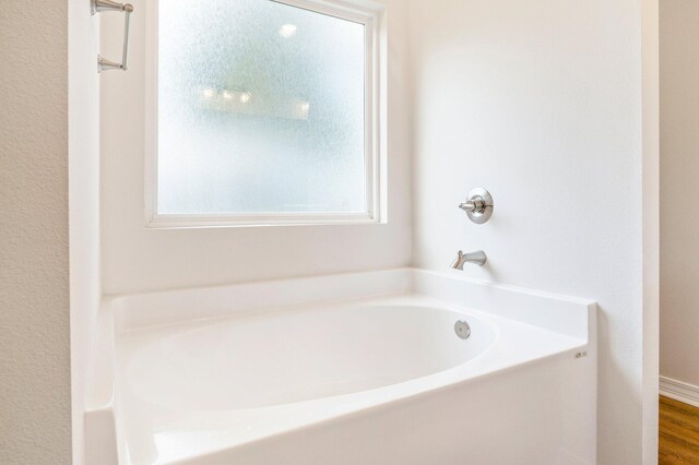 bathroom with a wealth of natural light, a washtub, and wood-type flooring