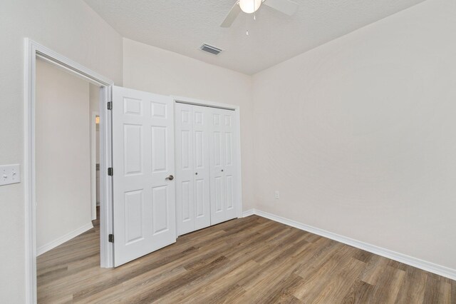 unfurnished bedroom with ceiling fan, a closet, and hardwood / wood-style flooring