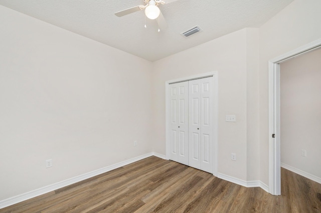 unfurnished bedroom with a textured ceiling, a closet, ceiling fan, and hardwood / wood-style flooring