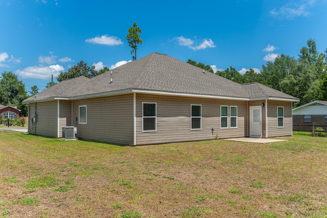 rear view of property with central AC unit, a patio area, and a lawn