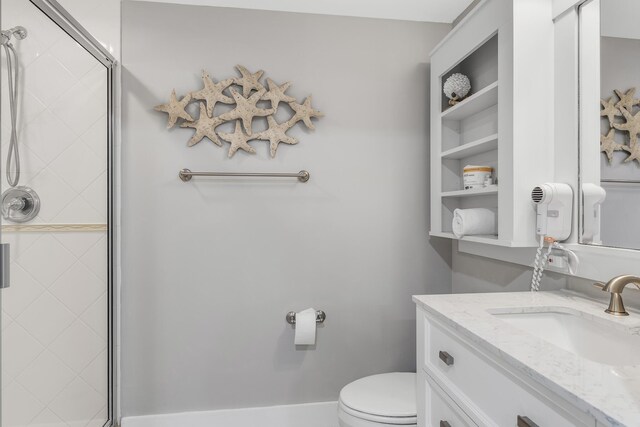 bathroom featuring an enclosed shower, vanity, and toilet