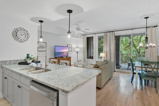 kitchen featuring decorative light fixtures, light hardwood / wood-style flooring, light stone countertops, and dishwashing machine