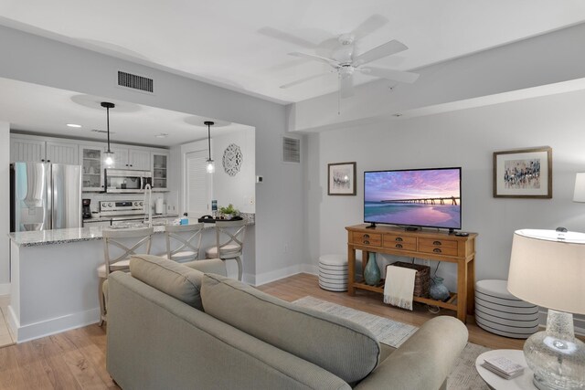 living room with light hardwood / wood-style flooring and ceiling fan