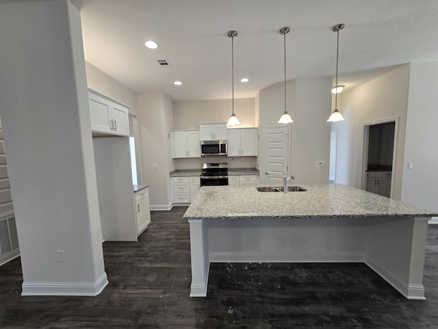 kitchen with stainless steel appliances, sink, white cabinetry, an island with sink, and hanging light fixtures