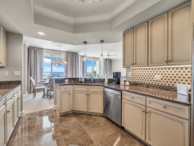 kitchen featuring cream cabinets, a peninsula, a sink, dishwasher, and a raised ceiling