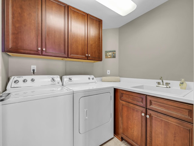 clothes washing area with separate washer and dryer, a sink, and cabinet space