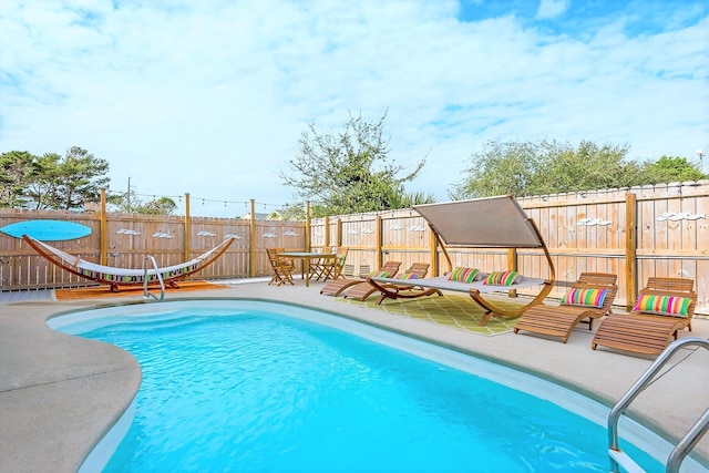 view of swimming pool featuring a fenced backyard, a water slide, and a patio area