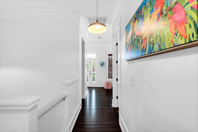 hall featuring baseboards, ornamental molding, visible vents, and hardwood / wood-style flooring