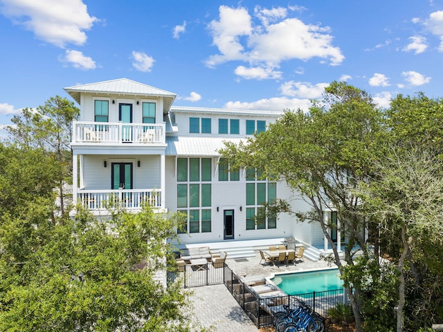 back of property with a fenced in pool, french doors, metal roof, a balcony, and fence private yard