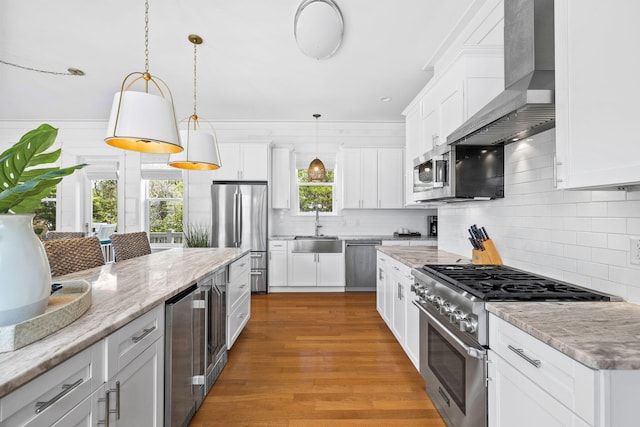 kitchen with light wood finished floors, beverage cooler, wall chimney exhaust hood, stainless steel appliances, and a sink