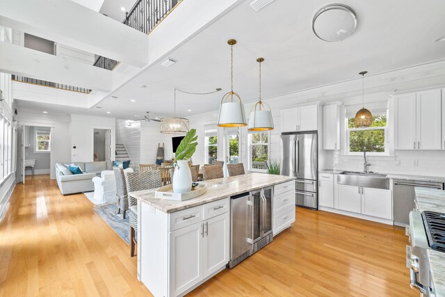 kitchen with light hardwood / wood-style flooring, white cabinetry, sink, a center island, and stainless steel appliances